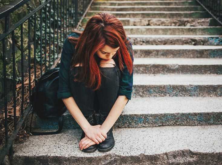 Photo: Woman sitting down on stairs with head in her lap